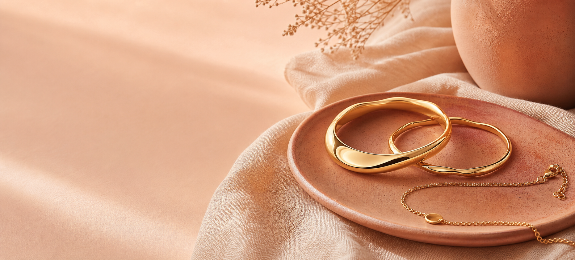 Gold bangles and a delicate bracelet on terracotta ceramic